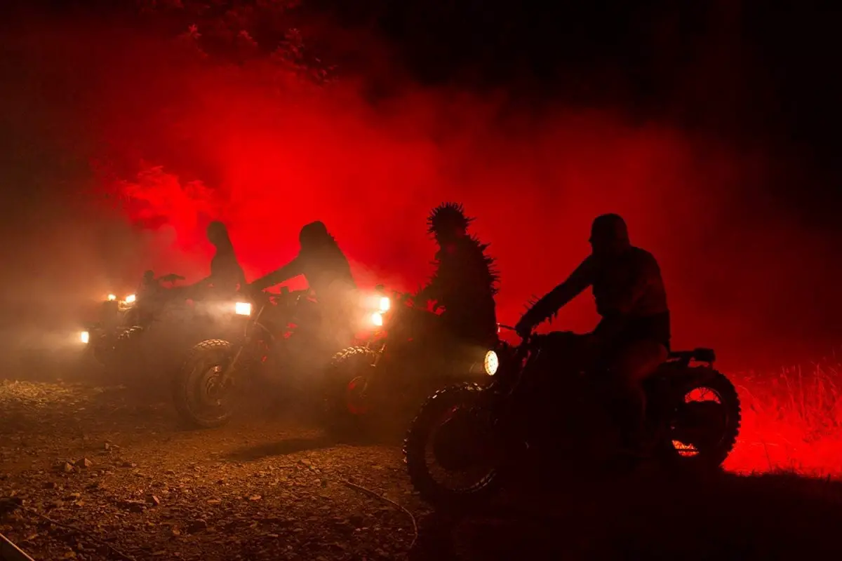 The Black Skulls on motorbikes lit by red light in Mandy