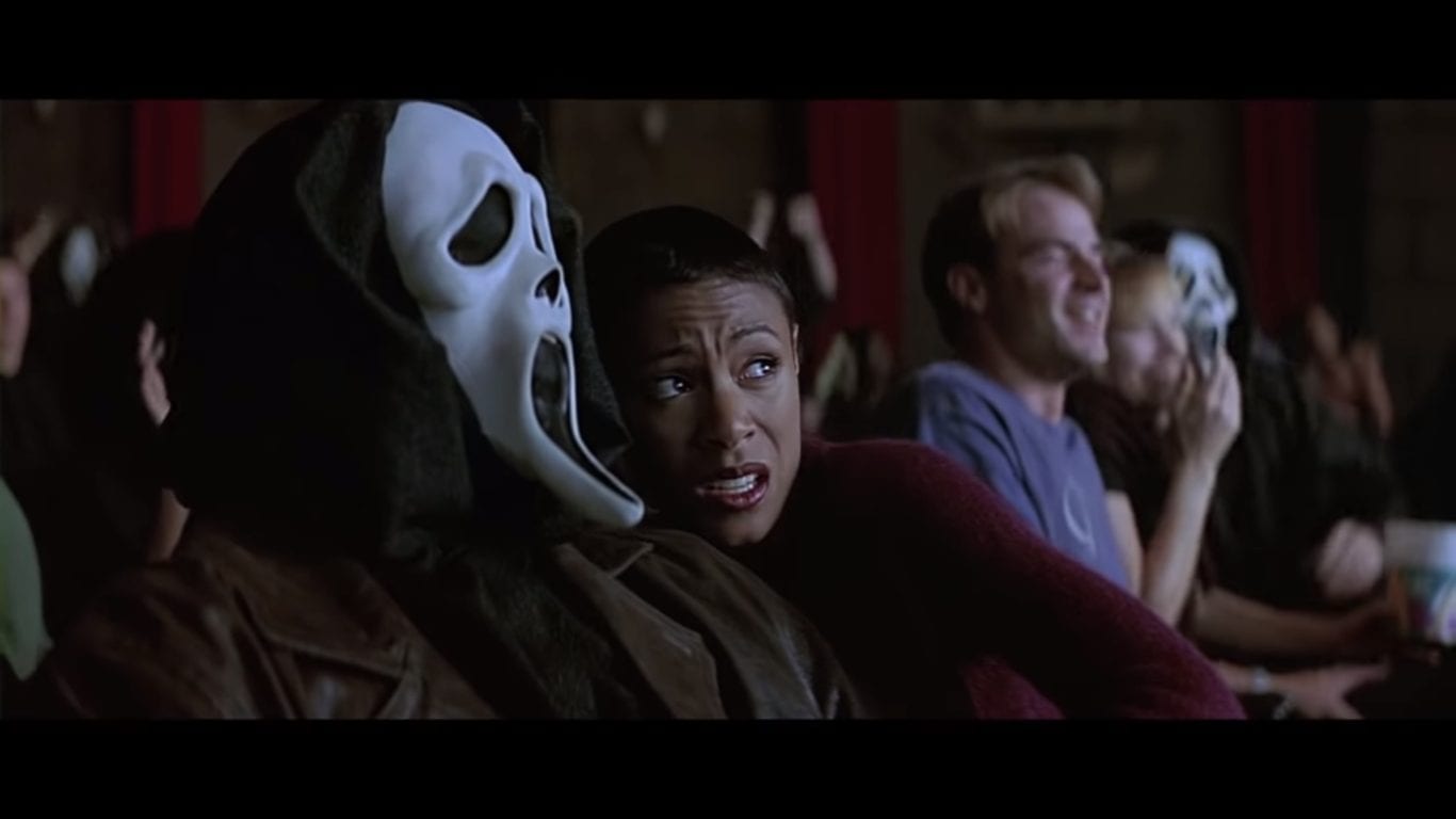 a man in the scream mask with his girlfriend in the cinema frightened by a scary movie