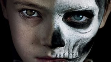 a boy with half his face painted like a skeleton