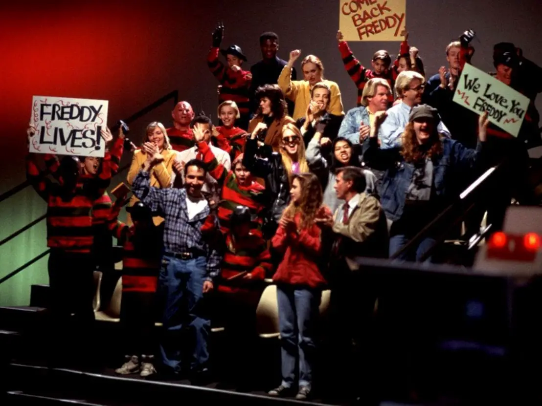 Audiences at a talk show cheer on Robert Englund as he surprises Heather Langenkamp in Freddy makeup in Wes Craven's New Nightmare.