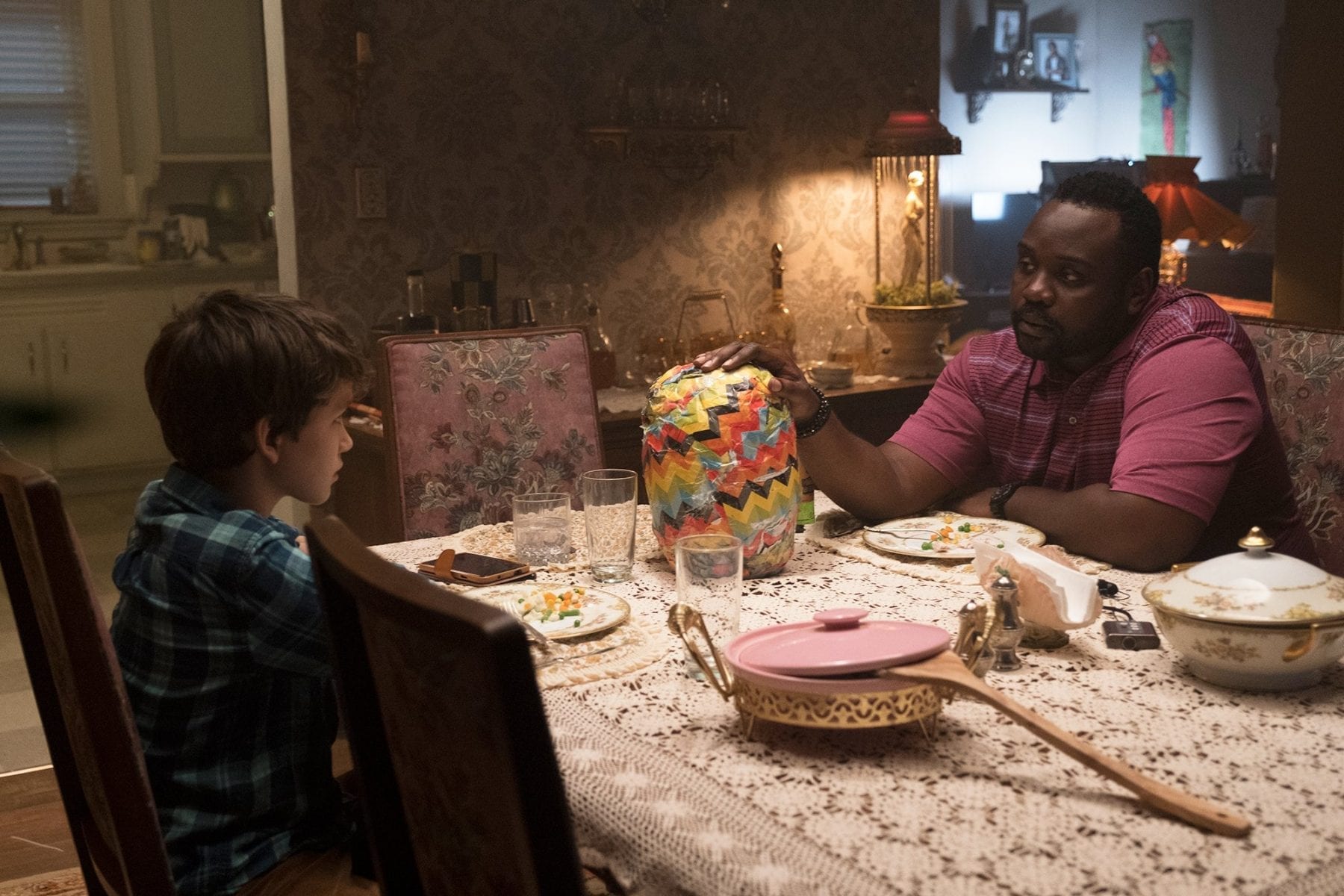 Detective Mke Norris (Brian Tyree-Henry) and Andy (Gabriel Bateman) talk over dinner, a strange "gift" in between them.