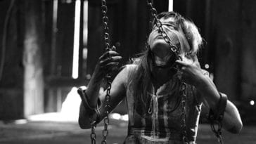 A young woman sits on a swing with a blindfold on