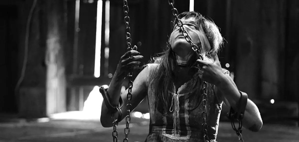 A young woman sits on a swing with a blindfold on