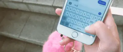 A female hand types text into an iphone