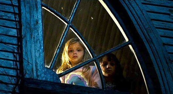 Little girl Chelsea looks out the upstairs window of her house, the ghost child Jodie standing next to her in The Amityville Horror (2005).