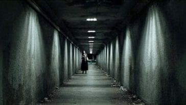 a woman walking down a tunnel at night