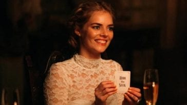 Grace holds up the card she has chosen which reads 'Hide and Seek' she is smiling