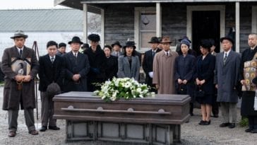 The Nakayama and Furuya families stand around the coffin of Mrs Furuya at her funeral