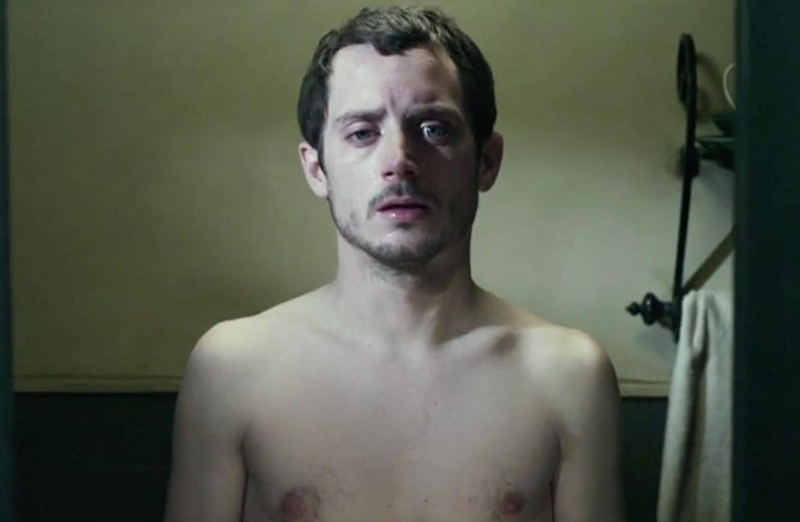 Frank stares at himself topless in a mirror. He looks tired and defeated.