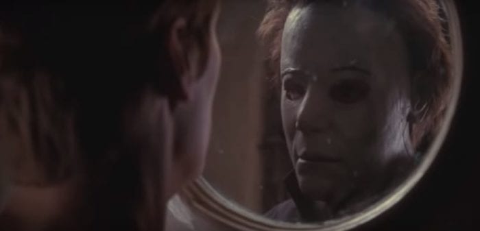 Laurie Strode comes face to face with her brother, masked killer Micheal Myers, as they stare at each other through a circular glass hole in a door