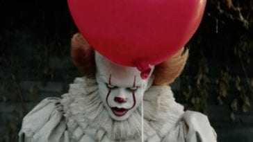 A clown holding a red balloon.
