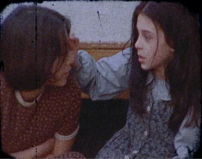 Young Lucie and Anna look at each other and talk quietly