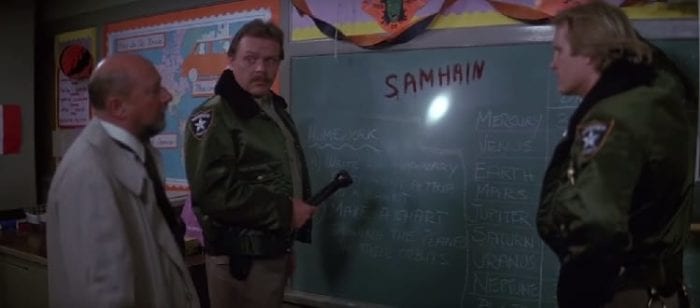 Two deputies and Dr Loomis stare at a chalkboard where SAMHAIN has been written in blood