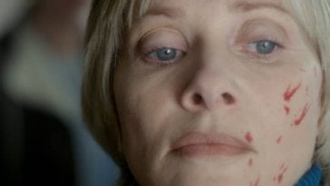 Barbara Crampton has blood on her face and stares off in the distance in We Are Still Here