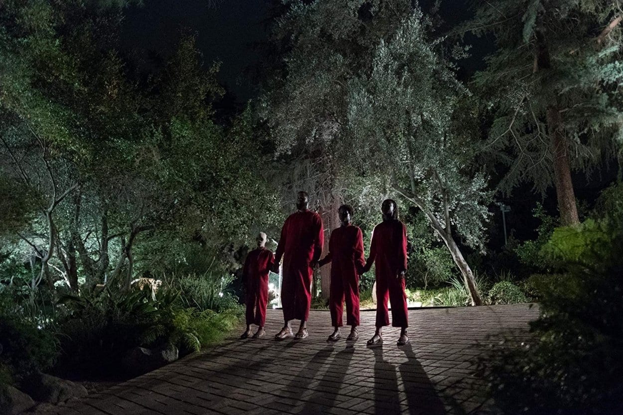 A Family of a boy, father, mother, and daughter, stand in the dark wearing red coveralls