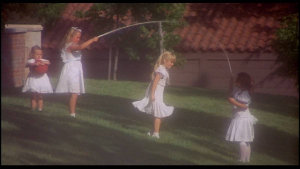 4 little girls in white dresses playing skipping rope