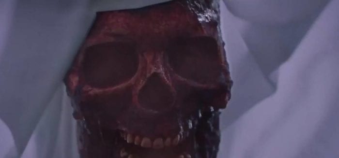 Close up shot of a bloody skull beneath a sheet.