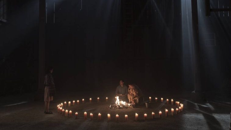 Chester sits in the dark amongst a circle of candles