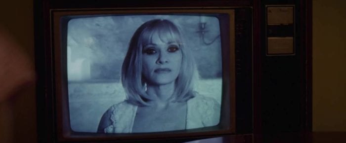 Barbara Crampton appears on a black-and-white TV set in Beyond the Gates