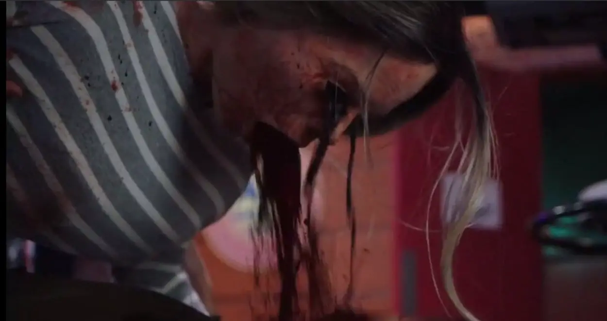 Close up shot of blood and small worms pouring out of a woman's eyes and mouth.