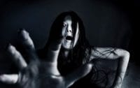 A dark figure of a woman screams and reaches out her hand