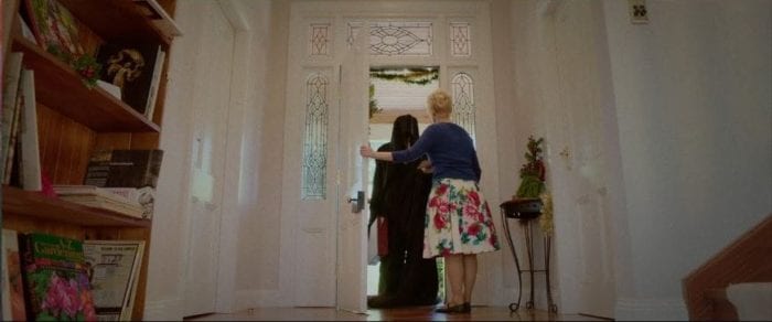 Diane invites a cloaked man into her home in Red Christmas