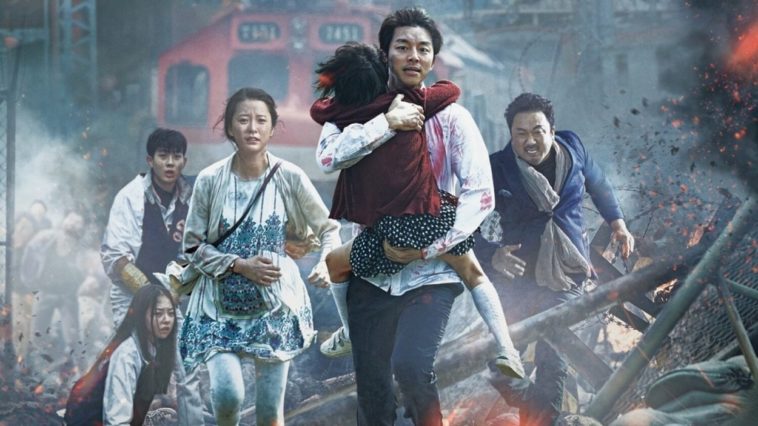 the main characters of the movie running away from the train and zombies, with wreckage all around them