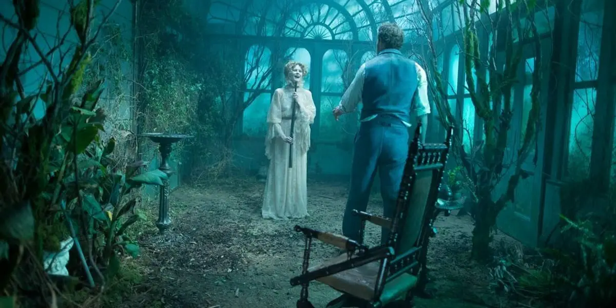 Eric stands with his back to the camera, his wife Ruby in front of him holding a gun below her chin as they stand in an overgrown greenhouse in Winchester
