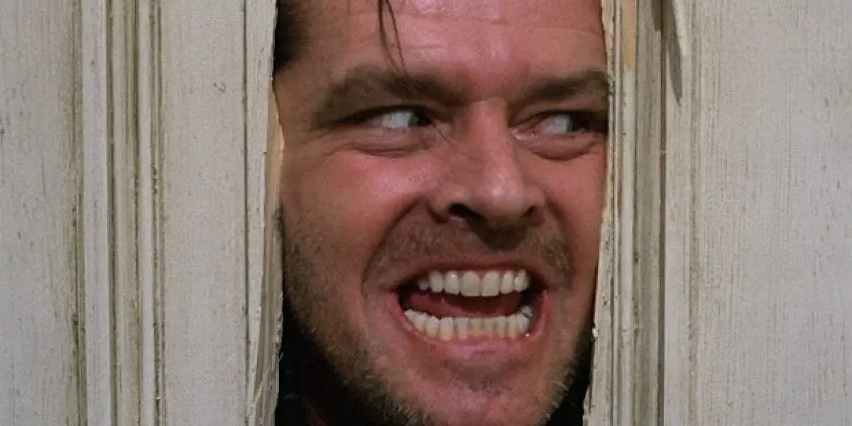 Jack Torrance peers through a broken door with a crazed look on his face