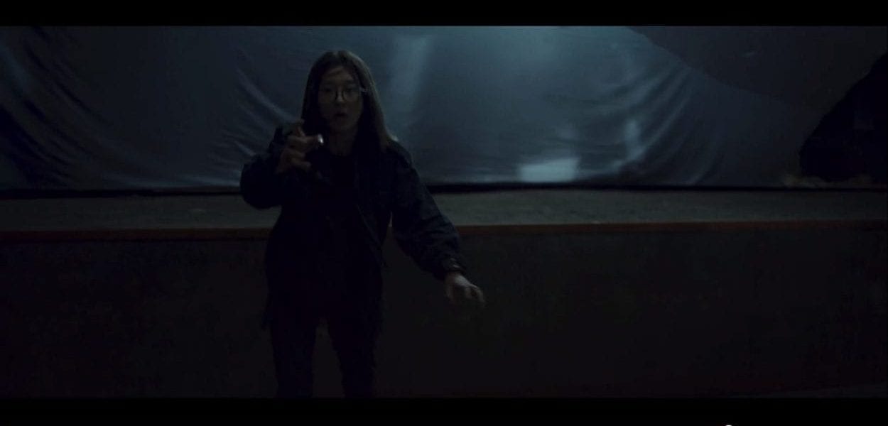 korean woman standing in front of a movie screen with her empty hand held out in front of her 
