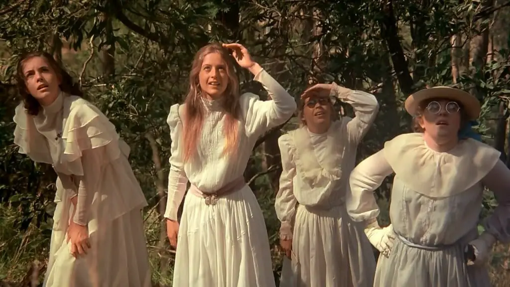 Four young girls, dressed in old fashioned white frocks stand side by side staring up at something
