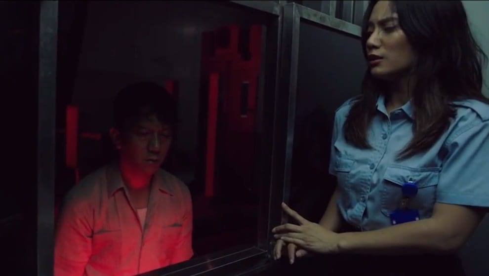 Maya looks frightened and confined in a booth as a harrowed looking man approaches her toll booth window.