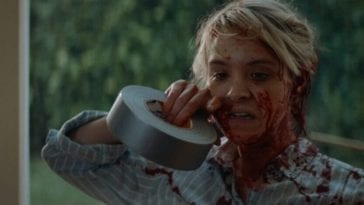 May (Brea Grant) rips some duct tape with her teeth as she’s covered in blood