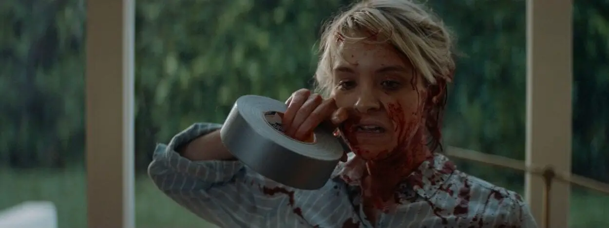 May (Brea Grant) rips some duct tape with her teeth as she’s covered in blood