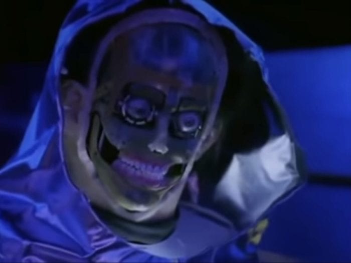 A man in a biohazard suit reveals his skeleton to be that of a robot