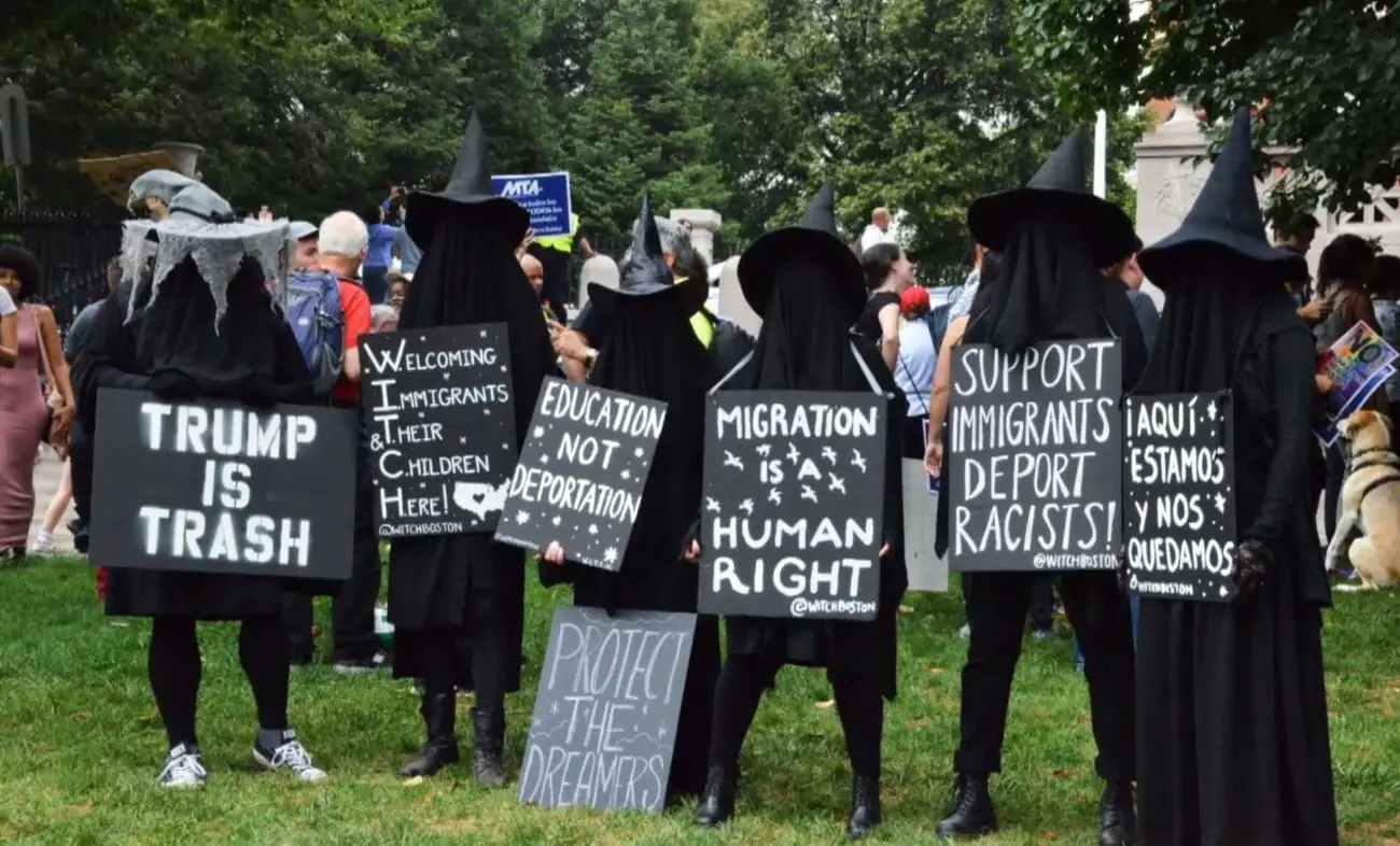 a scene of protesters holding anti-trump signs gather dressed as witches to support human rights