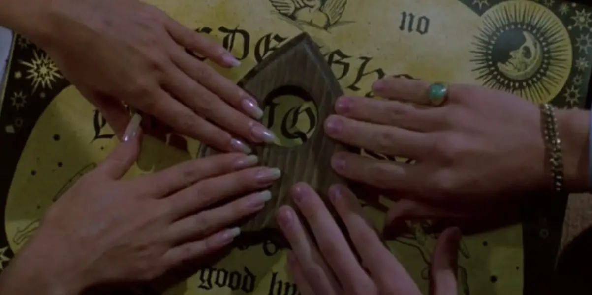 Four hands touching the planchette of a ouija board.