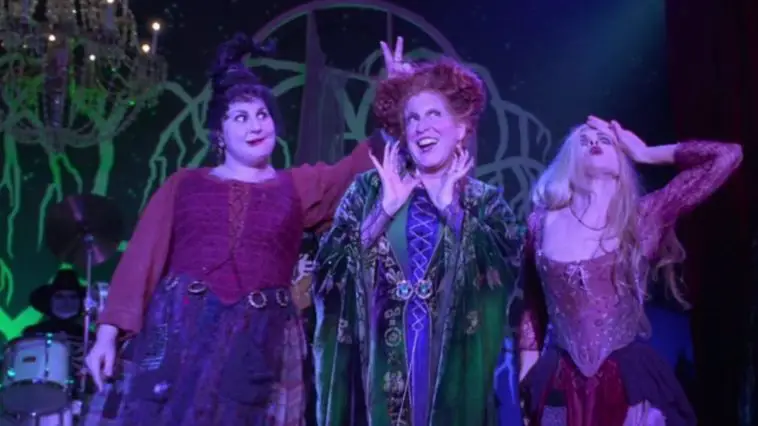 Mary (Kathy Najimy), Winifred (Bette Midler), and Sarah (Sarah Jessica Parker) Sanderson sing a song, with Mary putting two fingers up behind Winifred's head, in the film, "Hocus Pocus" (1993).
