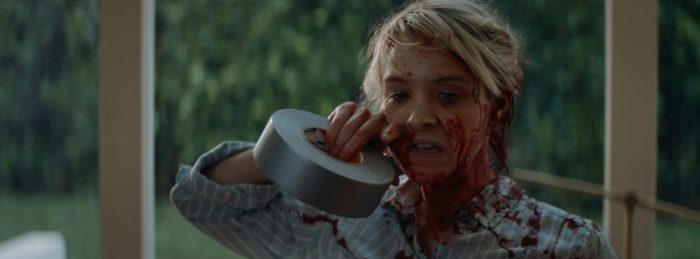 May (Brea Grant) rips duct tape with her teeth while covered in blood.