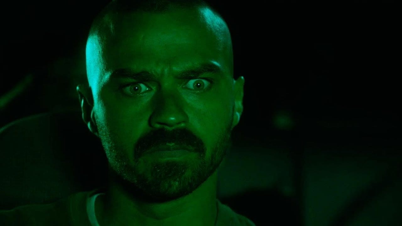 Todd, cast entirely in a deep green light, looking deeply troubled, eyes wide and brows furrowed.