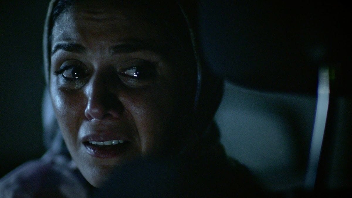 A woman looks in horror as tears fill up her eyes.