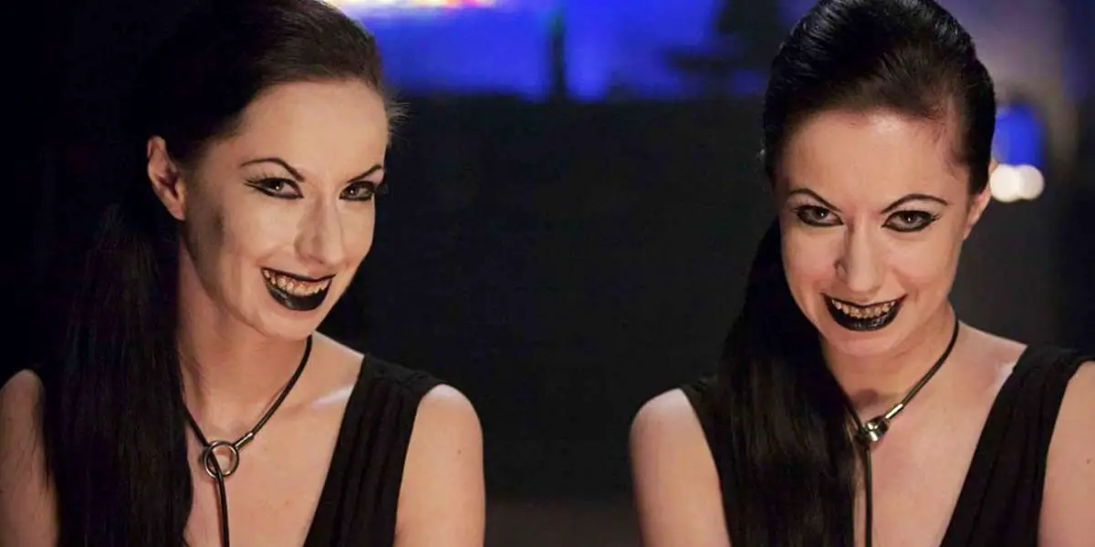 Soska sisters sit in a bar wearing black dresses and black lipstick in American Mary.