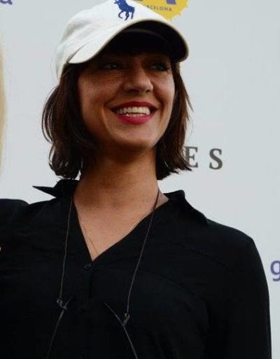 Ana Lily Amirpour smiles for a photo while wearing a Ralph Lauren cap.