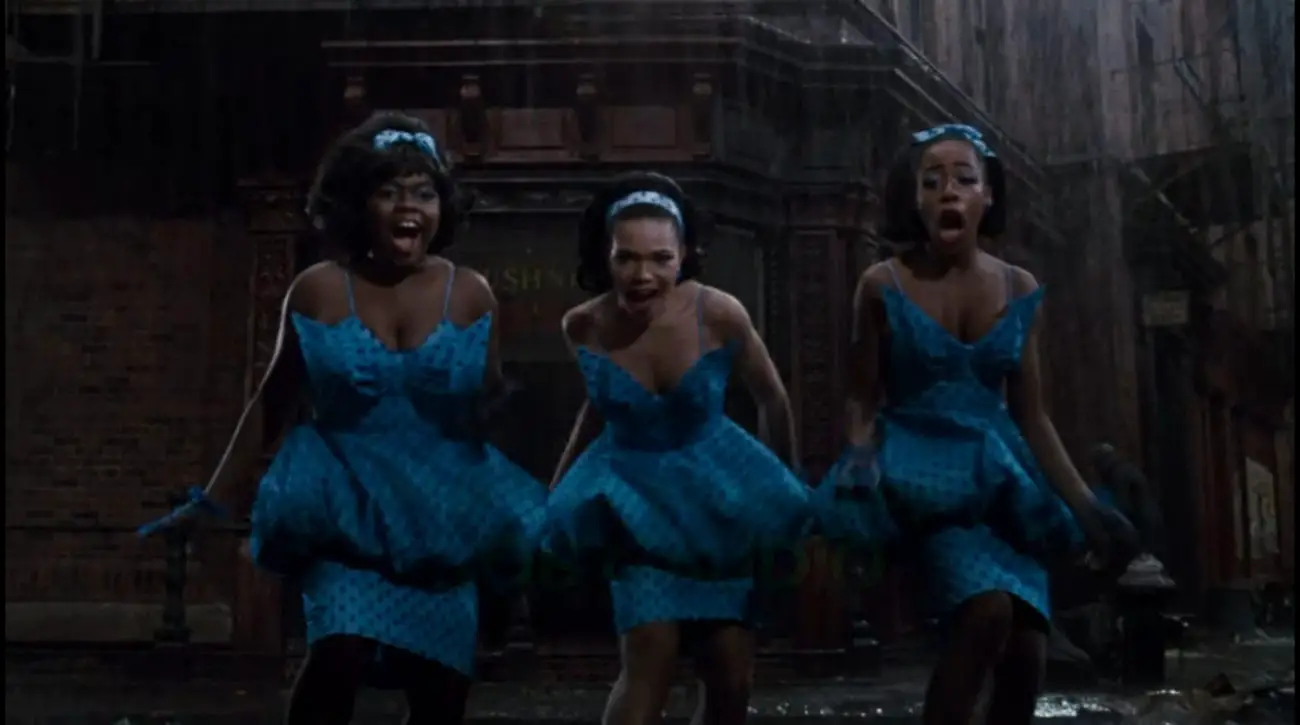 Ronette (Michelle Weeks), Chiffon (Tisha Campbell), and Crystal (Tichina Arnold) dance across the street in matching blue outfits, singing to the audience without getting wet, in the film, "Little Shop of Horrors" (1986).