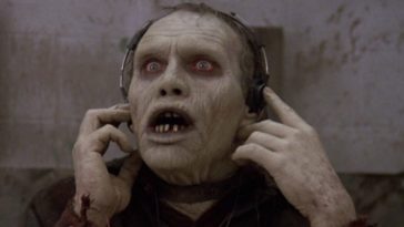 A zombie listens to something through headphones.
