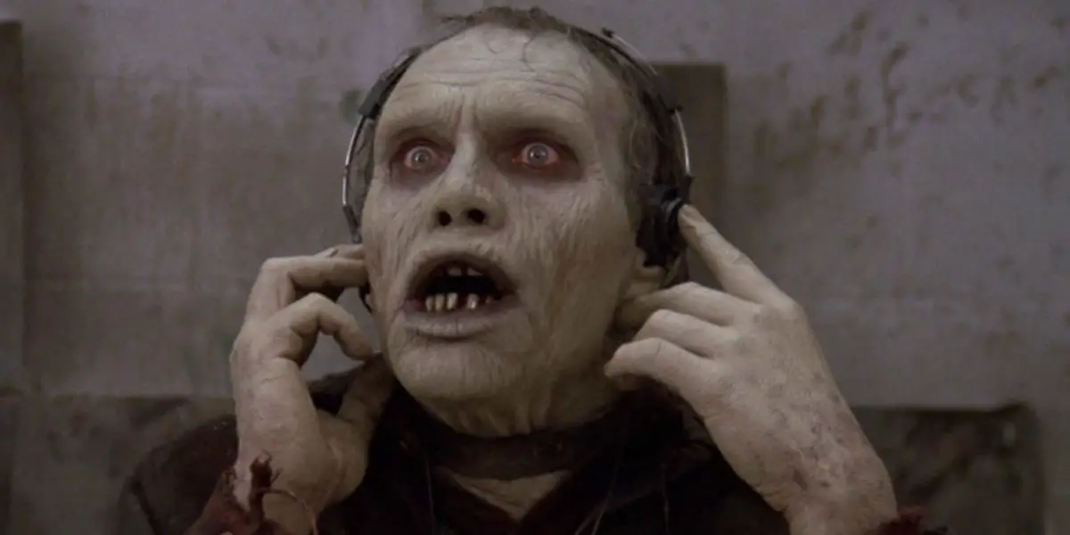 A zombie listens to something through headphones.