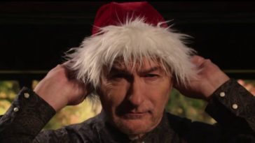 Joe Bob Briggs putting on a Santa hat