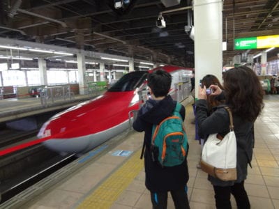 People take photographs of Super Komachi Shinkansen bullet train as it pulls into station.