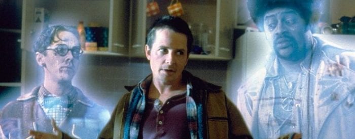 Stuart (left) and Cyrus (right) are semi-transparent ghosts, both looking at Michael J. Fox, who is centre frame