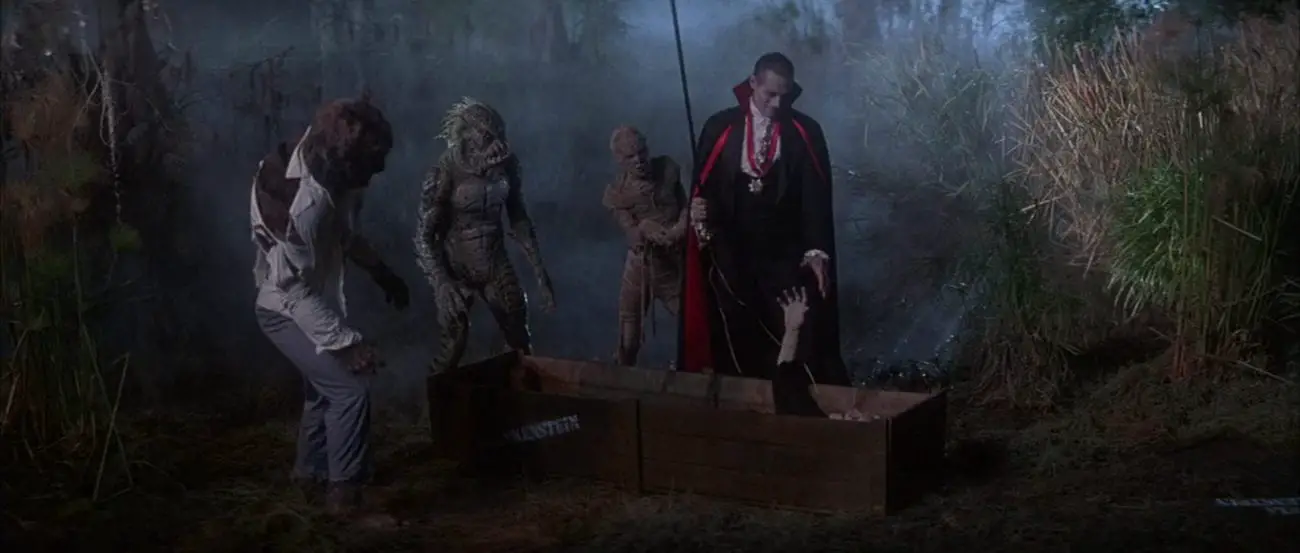Wolfman (Jonathan Gries), Gillman (Tom Woodruff, Jr.), and the Mummy (Michael Reid MackKay) look on as Count Dracula (Duncan Regehr) reaches down toward the extended hand of the Frankenstein monster (Tom Noonan), who's lying in a crate, in the film, "The Monster Squad" (1987).